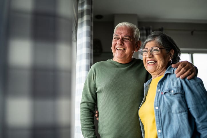 Senior couple looking through the window at home