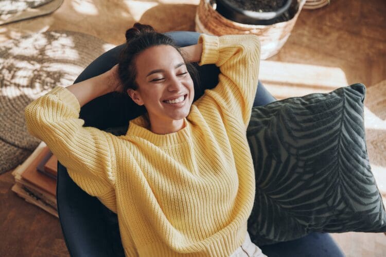 Happy woman leaning back on chair with hands behind head