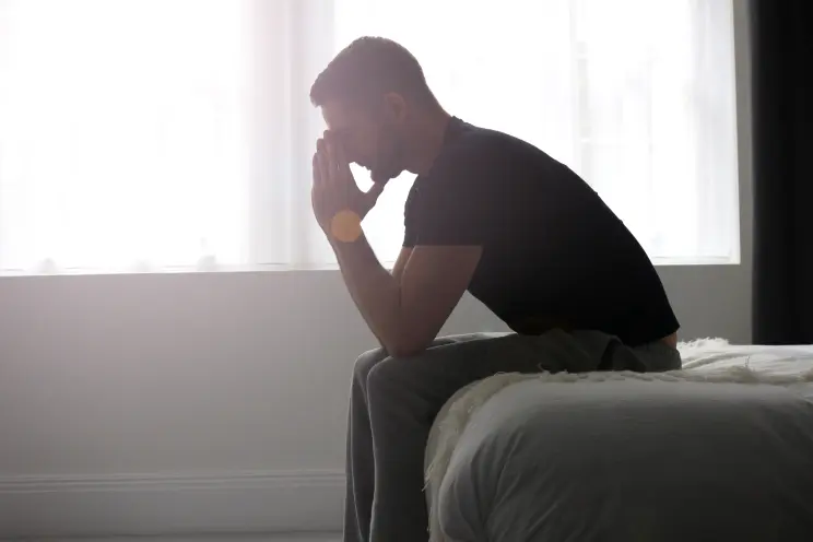 sad man sitting on the bed with his head in his hands - depression treatment